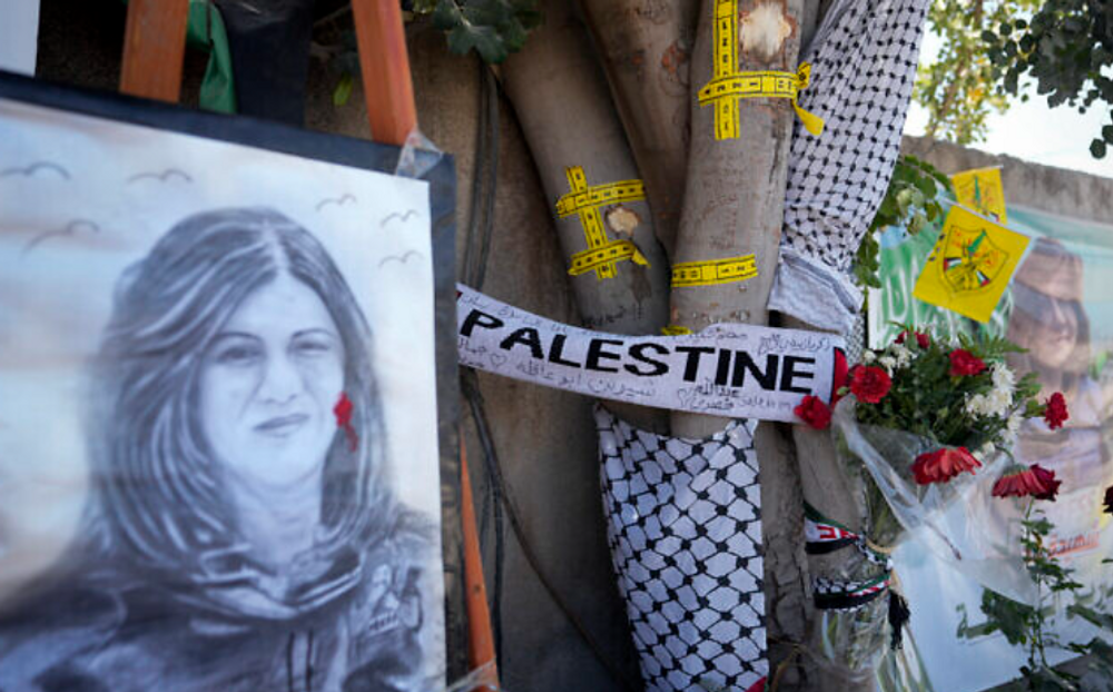Du ruban jaune marque les impacts de balles sur un arbre et un portrait et des fleurs forment un mémorial sur le site où la journaliste palestino-américaine d'Al-Jazeera Shireen Abu Akleh a été abattue dans la ville de Jénine  le 19 mai 2022.