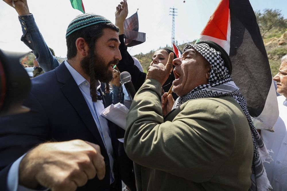 Knesset member for Israel's Religious Zionism party Tzvi Sukkot (L) is confronted as he tries to interrupt a rally by Palestinian activists at the entrance of Huwara in the West Bank.