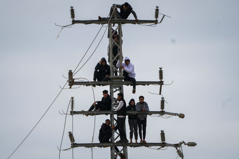 Youth watch from an electric pole Israeli hostages being handed over to the Red Cross by Hamas terrorists in Nuseirat, central Gaza Strip