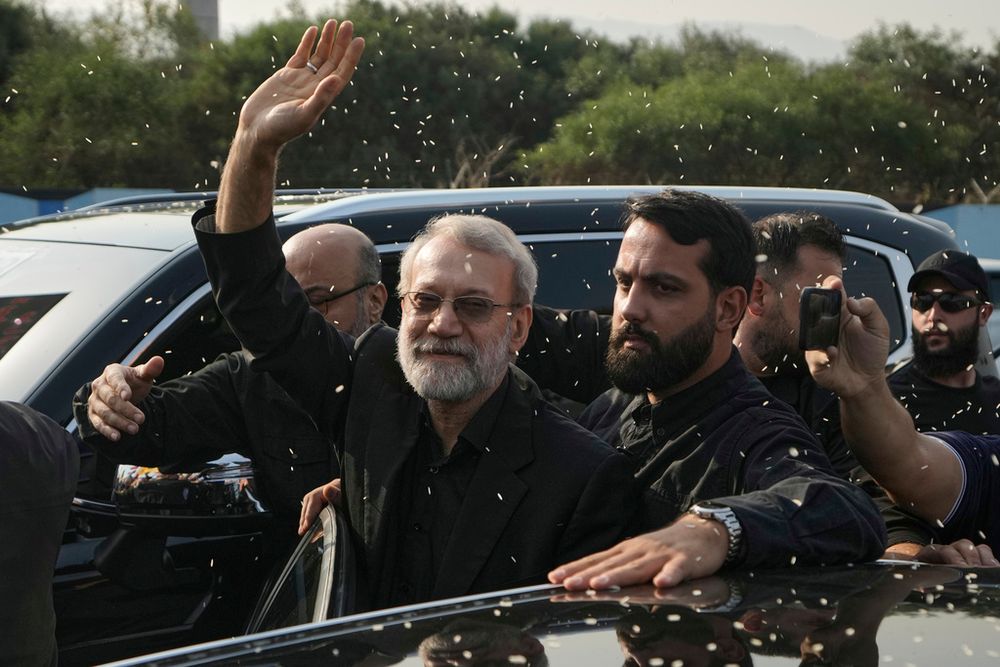 علی لاریجانی ، مرکز ، رئیس شورای امنیت ملی ایران ، حرکات به عنوان هواداران حزب الله چهارشنبه برنج را برای استقبال از وی در خارج از فرودگاه بین المللی رافیک حریری در بیروت ، لبنان پرتاب می کنند.