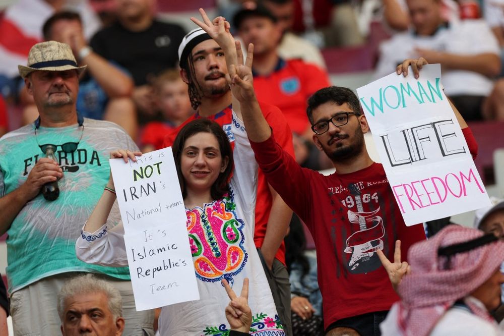 Iran supporters gesture while holding placards before the start of the Qatar 2022 World Cup Group B football match between England and Iran at the Khalifa International Stadium in Doha, Qatar, on November 21, 2022.