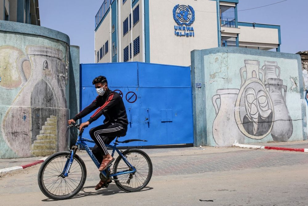A Palestinian rides a bicycle past the closed gate of a school run by the United Nations Relief and Works Agency for Palestinian Refugees (UNRWA) in the city of Rafah in the southern Gaza Strip on April 6, 2021.