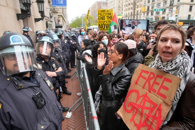 Police in riot gear stand guard as pro-Palestinian students chant slogans outside the Columbia University campus.