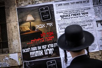 An ultra-Orthodox Jew stops to read a broadsheet on the IDF draft law in the neighborhood of Mea Shearim, in Jerusalem, March 15, 2024.