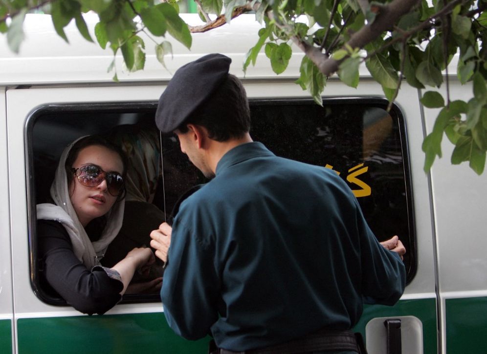 AFP PHOTO/BEHROUZ MEHRI Un membre de la police des mœurs met en garde une jeune femme pour son port du voile jugé non réglementaire à Téhéran, en Iran