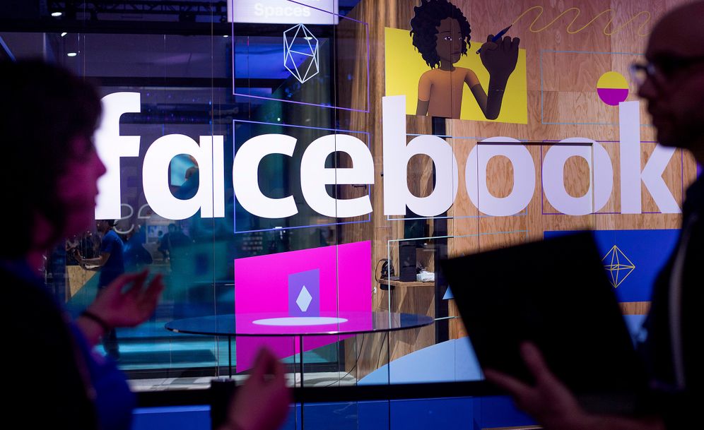 FILE - In this Tuesday, April 18, 2017, file photo, conference workers speak in front of a demo booth at Facebook's annual F8 developer conference, in San Jose, Calif.