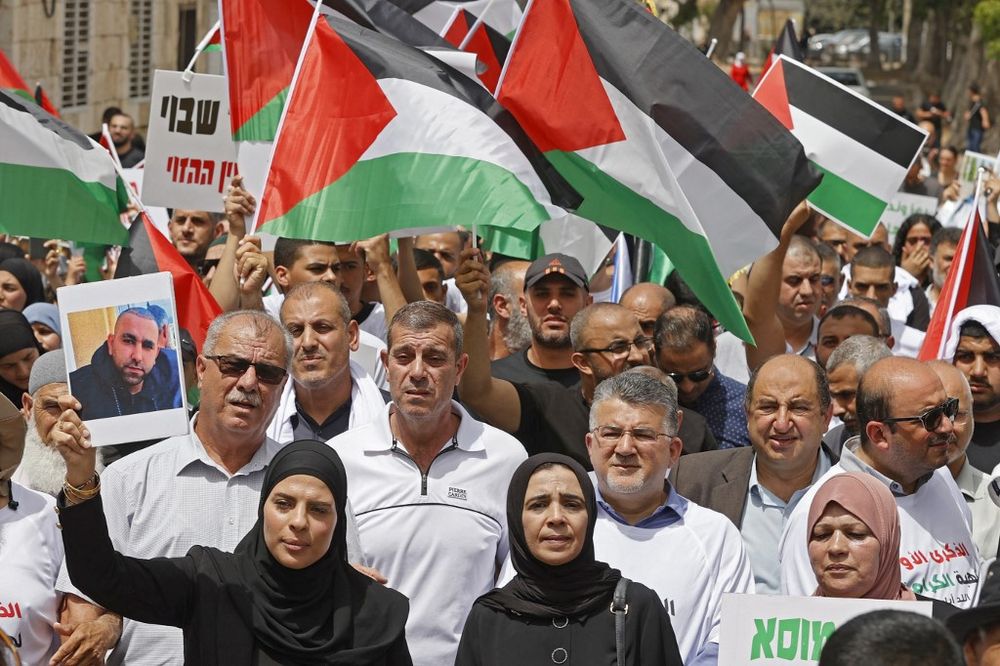 Des Israéliens arabes se rassemblent avec des drapeaux palestiniens dans la ville mixte de Lod près de Tel Aviv le 13 mai 2022, un an après qu'un membre de leur communauté a été tué lors de violences intercommunautaires