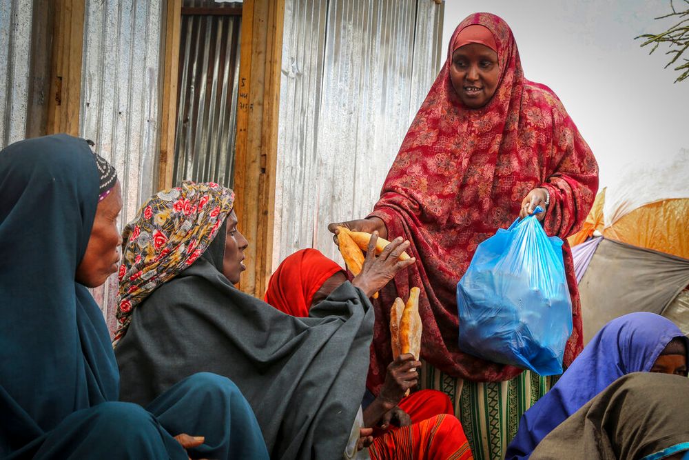 Somalis who fled drought-stricken areas receive charitable food donations from city residents after arriving at a makeshift camp for the displaced on the outskirts of Mogadishu, Somalia, on June 30, 2022.