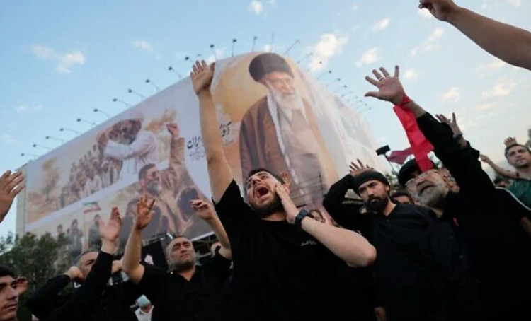 Des personnes en deuil scandent des slogans sur la place de la Révolution islamique lors du cortège funèbre du guide suprême iranien Ali Khamenei, tué, sous un immense portrait de ce dernier à Téhéran, le 6 juillet 2026.