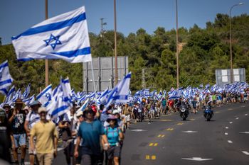 Demonstrators wave Israeli flags as they march from Tel Aviv to Jerusalem to protest against the government's judicial reform plan.
