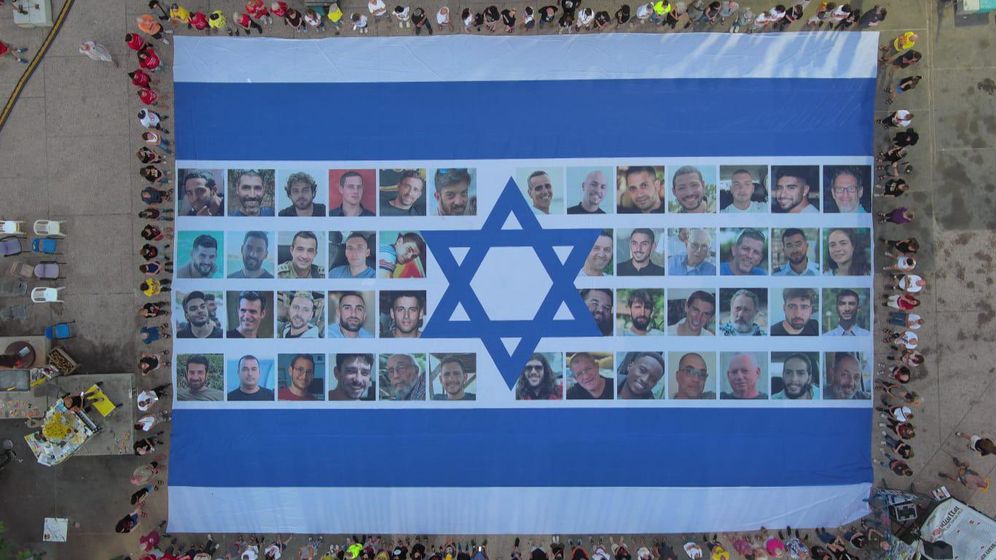 Hostage and Missing Families Forum Le drapeau israélien avec les photos des otages déployé sur la place des otages, à 06h29, heure du début des attaques terroristes du 7 octobre