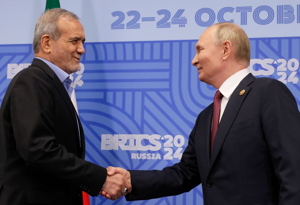 Russian President Vladimir Putin (right) and Iranian President Masoud Pezeshkian shake hands during their meeting on the sidelines of the BRICS summit in Kazan, Russia