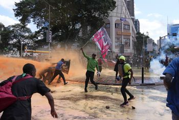 Protesters scatter as Kenya police spray water canon at them during a protest over proposed tax hikes in a finance bill in downtown Nairobi, Kenya Tuesday, June. 25, 2024.
