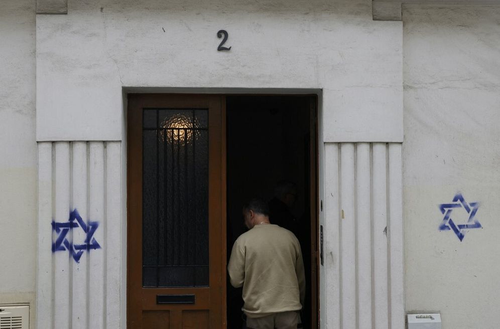 A man enters a building whose facade is covered with Stars of David painted during the night, in the Alesia district of Paris, on October 31, 2023.