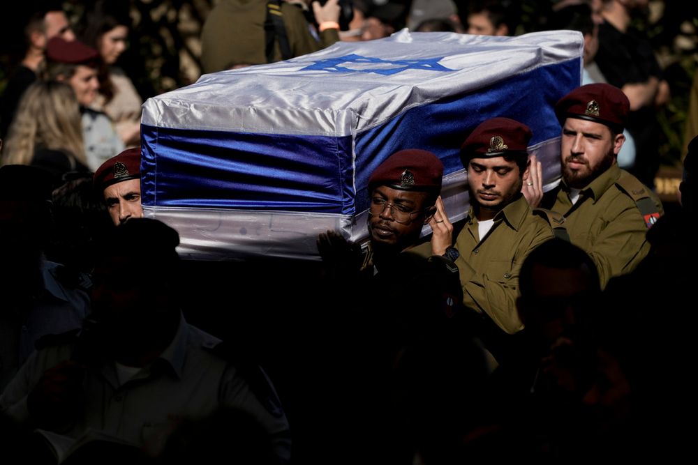 Soldados israelenses carregam o caixão coberto com a bandeira do sargento mestre.  Gal Meir Eizenkot, 25 anos, morta em combates em Gaza, no cemitério militar de Herzliya, Israel.