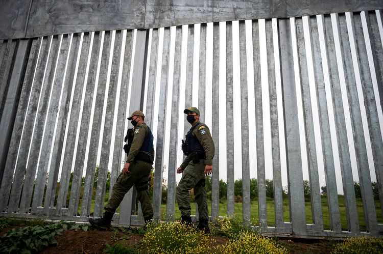 Police officers patrol alongside a steel wall at Evros river at the Greek-Turkish border, Greece, on May 21, 2021.
