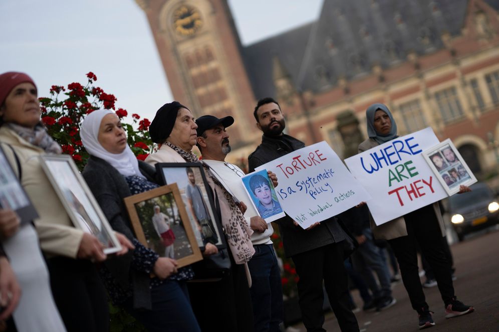 FILE - Demonstrators display pictures of people, they say disappeared in Syria, outside the International Court of Justice in The Hague, Netherlands.