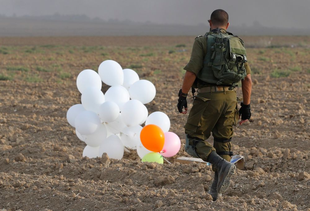 illustration - Un soldat israélien s'approche d'un engin incendiaire lancé depuis Gaza vers la localité israélienne frontalière de Nahal Oz, le 19 octobre 2018
