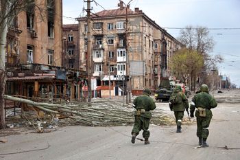 Servicemen of the militia from the Donetsk People's Republic walk past damaged apartment buildings in Mariupol, Ukraine, on April 16, 2022.