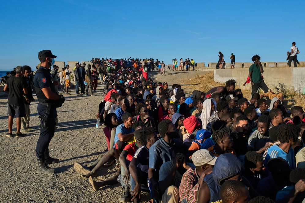 AP/Bernat Armangue Migrants who crossed from Morocco into Spain line up for food distribution on a beach in the Spanish enclave of Ceuta, Monday, Aug. 3, 2026.