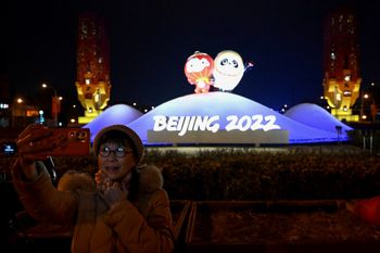 A woman takes a selfie in front of an installation displaying mascots of the 2022 Beijing Winter Olympic and Paralympic Games, along a street in Beijing, China on January 19, 2022.
