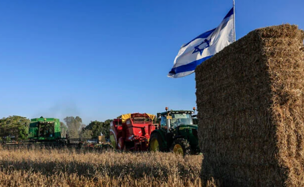 Un drapeau israélien flotte au-dessus d’un champ agricole du kibboutz Nahal Oz, près de la frontière avec la bande de Gaza, alors que des habitants participent aux célébrations traditionnelles de Chavouot, le 22 mai 2026.
