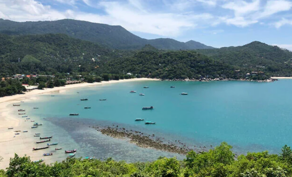 Sur cette photo d'archive datée du 5 juillet 2020, des bateaux de pêche et des embarcations utilisées pour transporter les touristes sont à l'arrêt le long d'une plage déserte sur l'île touristique très prisée de Koh Phangan, en Thaïlande.