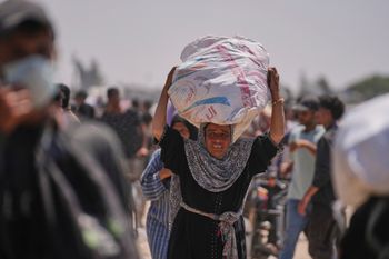 A Palestinian woman carries a bag containing food and humanitarian aid delivered by the Gaza Humanitarian Foundation, a U.S.-backed organization, in Rafah, southern Gaza Strip