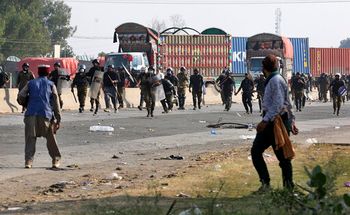 Police officers chase supporters of Tehreek-e-Labiak Pakistan, a radical Islamist party, during their protest march toward the capital of Islamabad, on a highway in the town of Sadhuke of eastern Pakistan, October 27, 2021.