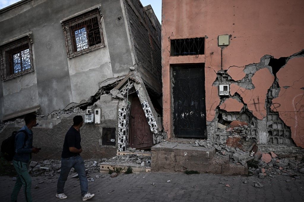سكان يسيرون بجوار المنازل المتضررة في قرية مولاي إبراهيم الجبلية في المغرب بعد زلزال الأطلس الكبير