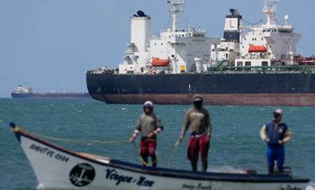 Des pêcheurs passent devant un pétrolier dans le golfe du Venezuela, au large de Punta Cardon, au Venezuela, le 14 janvier 2026. 
