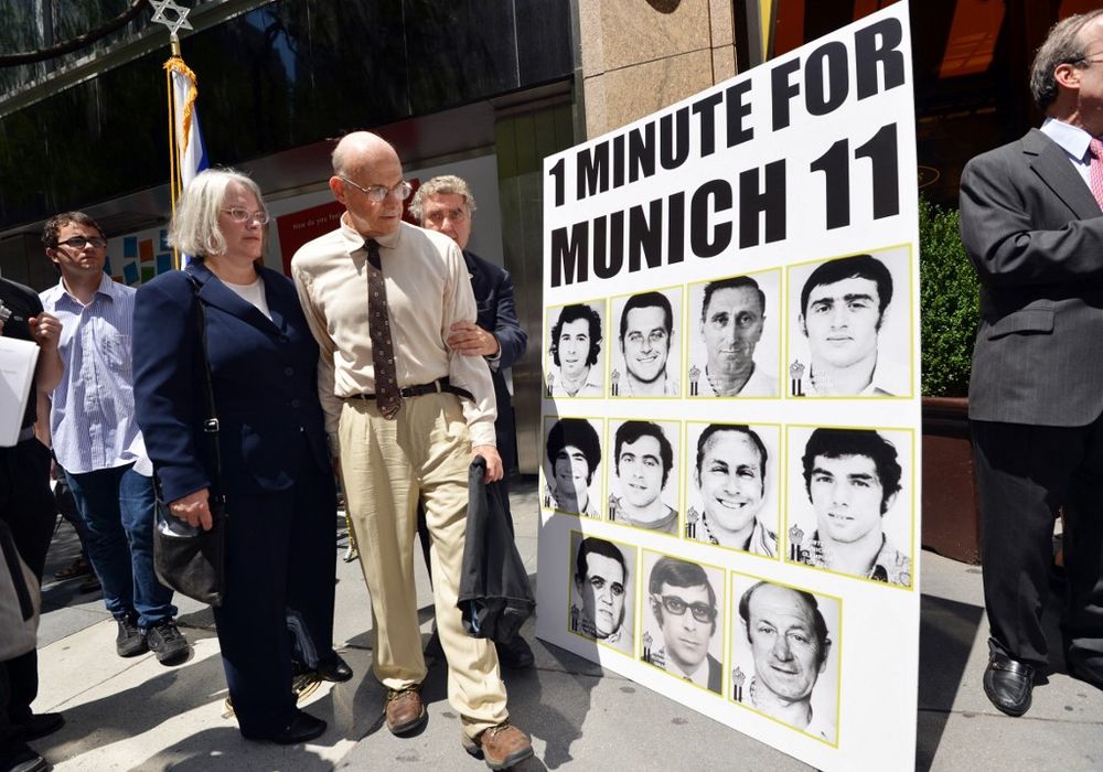 Avi Melamed (2nd L), surviving member of the 1972 Israeli Olympic team, walks past a poster in a moment of silence on July 27, 2012 in New York, US, to honor the 11 Israeli Olympic athletes killed at the Munich games.