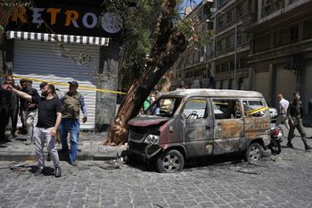 Syrian security personnel inspect a burned vehicle near the Four Seasons Hotel after two explosions rocked the area earlier while Syrian President Ahmad al-Sharaa was meeting French President Emmanuel Macron at the presidential palace, in Damascus, Syria, Tuesday, July 7, 2026