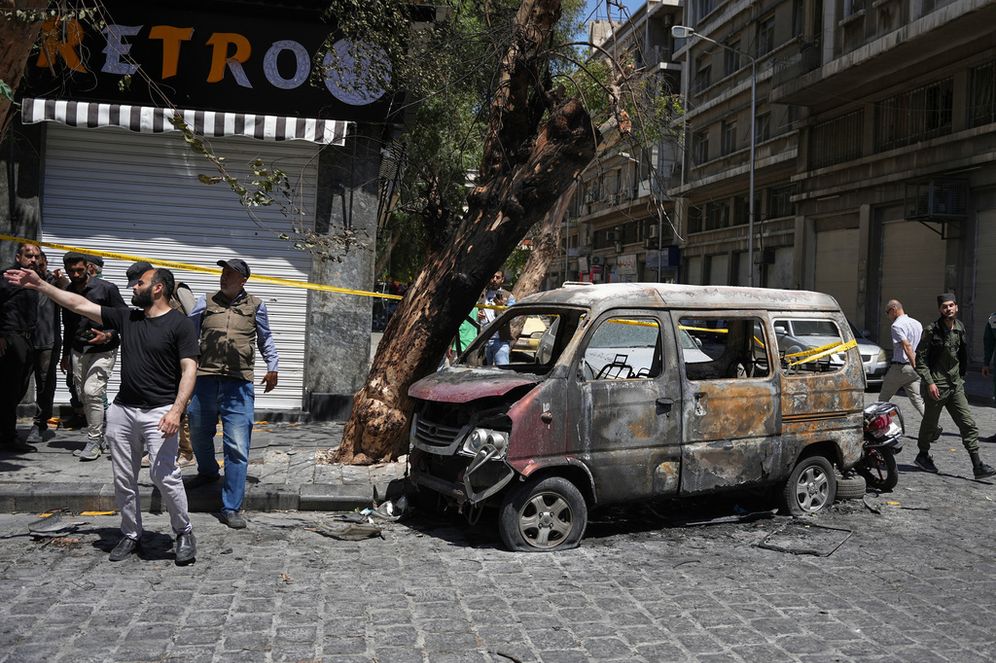 (AP Photo/Omar Albam) Syrian security personnel inspect a burned vehicle near the Four Seasons Hotel after two explosions rocked the area earlier while Syrian President Ahmad al-Sharaa was meeting French President Emmanuel Macron at the presidential palace, in Damascus, Syria, Tuesday, July 7, 2026