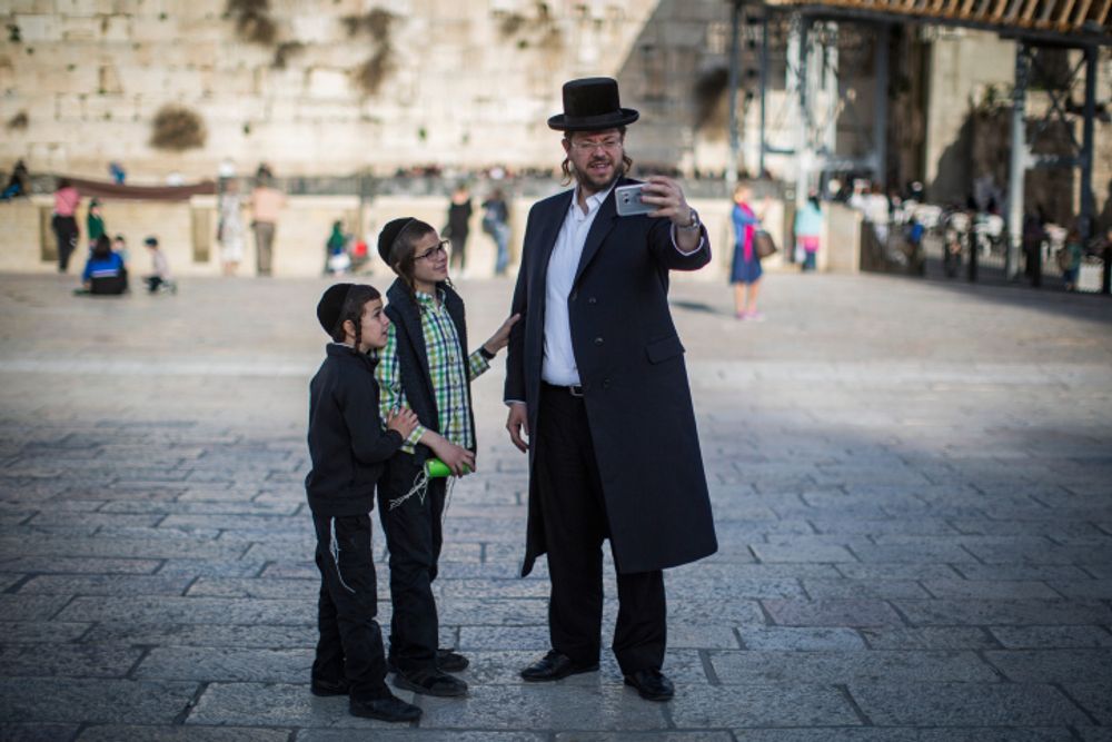 An ultra-Orthodox Jewish man takes a selfie with his children at the Western Wall in the Jewish Quarter of Jerusalem's Old City on February 26, 2017.