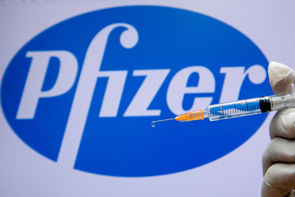 An Israeli medical worker holding a syringe with the coronavirus vaccine next to the Pfizer company logo in Jerusalem on December 10, 2020.