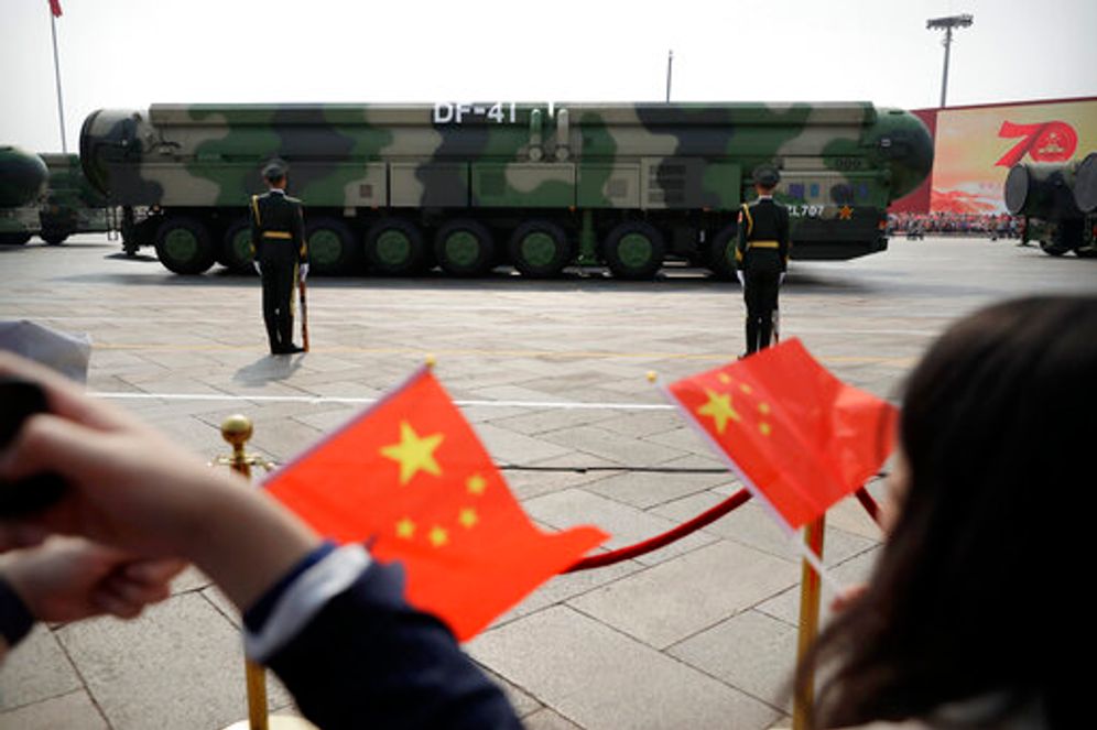 Spectators wave Chinese flags as military vehicles carrying DF-41 ballistic missiles roll past during a parade to commemorate the 70th anniversary of the founding of Communist China in Beijing on October 1, 2019.