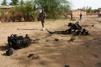 جنود نيجيريون يسيرون بالقرب من الأنقاض بعد أن فجر انتحاريون أنفسهم داخل ثكنة عسكرية في أغاديز، شمال النيجر