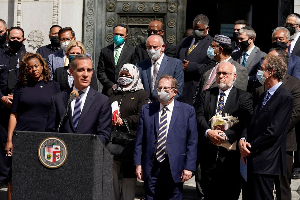 Los Angeles Mayor Eric Garcetti, at podium, speaks in front of civic and faith leaders outside City Hall in Los Angeles, on May 20, 2021.