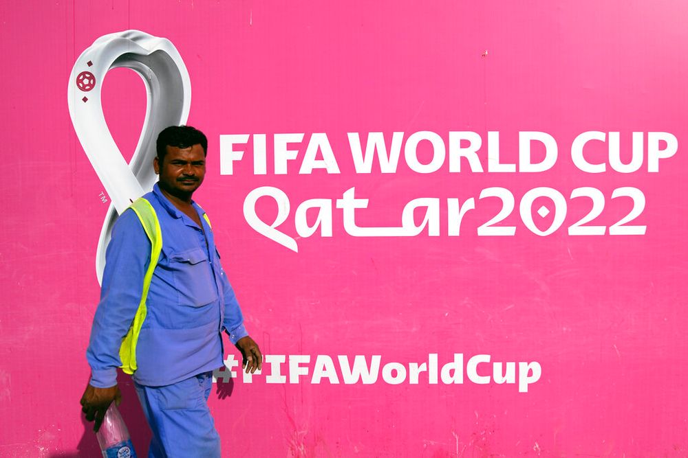 A worker walks past a billboard announcing the 2022 FIFA World Cup in Doha, Qatar.