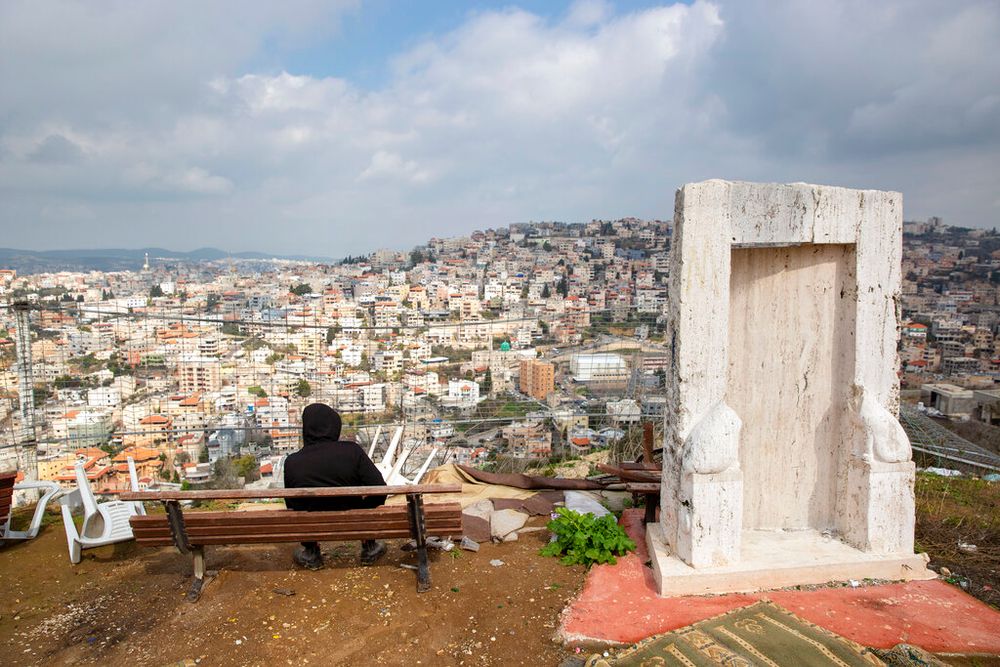 An Israeli Arab youth sits at a viewpoint overlooking the northern Israeli town of Umm al-Fahm, on February 4, 2020.