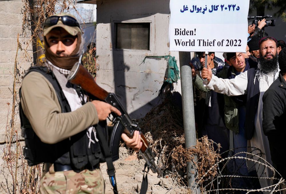 A Taliban fighter stands guard in front of protesters condemning U.S. President Joe Biden's decision to freeze Afghan assets in Kabul, Afghanistan.