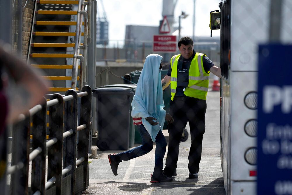 A man thought to be a migrant is directed to board a waiting transfer bus in Dover, southeast England.