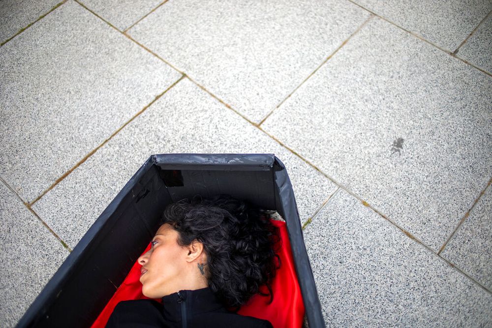 A woman lays in a coffin representing women killed in domestic violence in front of Tel Aviv's district court, Israel.