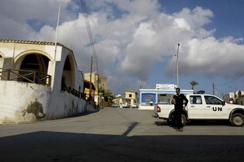 FILE - A UN police officer walks in front of a UN vehicle at the square of Pyla village at the UN buffer zone, outskirt of coastal city of Larnaca, Cyprus.