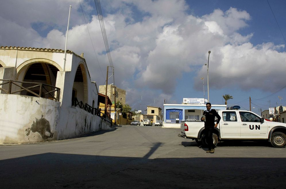 FILE - A UN police officer walks in front of a UN vehicle at the square of Pyla village at the UN buffer zone, outskirt of coastal city of Larnaca, Cyprus.