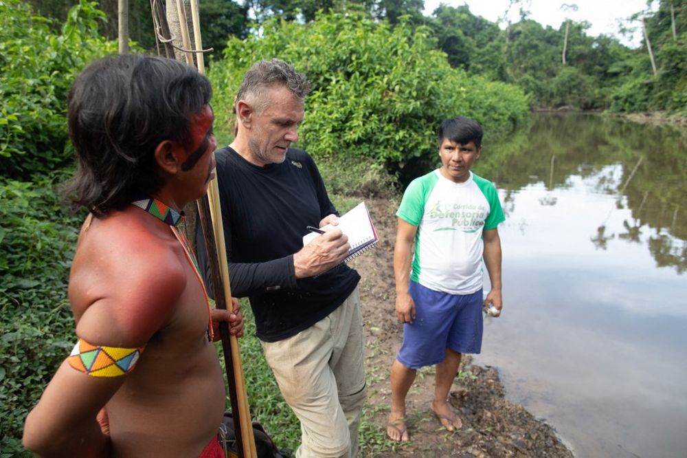 Foreign correspondent Dom Phillips (C) talks to two indigenous men in Aldeia Maloca Papiú, Roraima State, Brazil, on November 16, 2019.