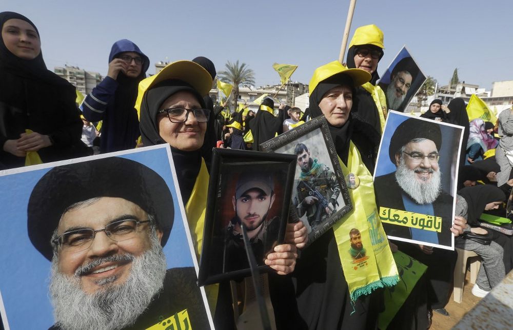 Supporters of Lebanon's Iran-backed Shiite group Hezbollah lift portraits of the group's leader Hassan Nasrallah as they rally to attend his speech, broadcast on a giant screen, in the southern city of Nabatiyeh, on May 9, 2022.