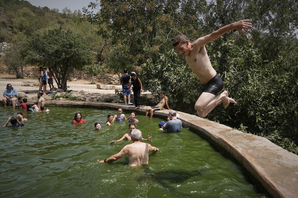 A man jumps in the water as people cool off in the Ein Lavan spring, amid a heat wave, in the outskirts of Jerusalem Wednesday