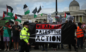 Des policiers surveillent des manifestants tenant une banderole lors d'une manifestation de soutien au groupe pro-palestinien Palestine Action, à Trafalgar Square, dans le centre de Londres, le 23 juin 2025. 